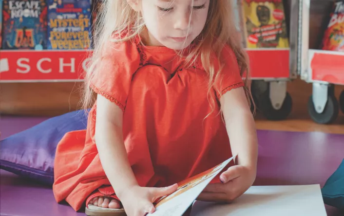 Girl reading a Scholastic book